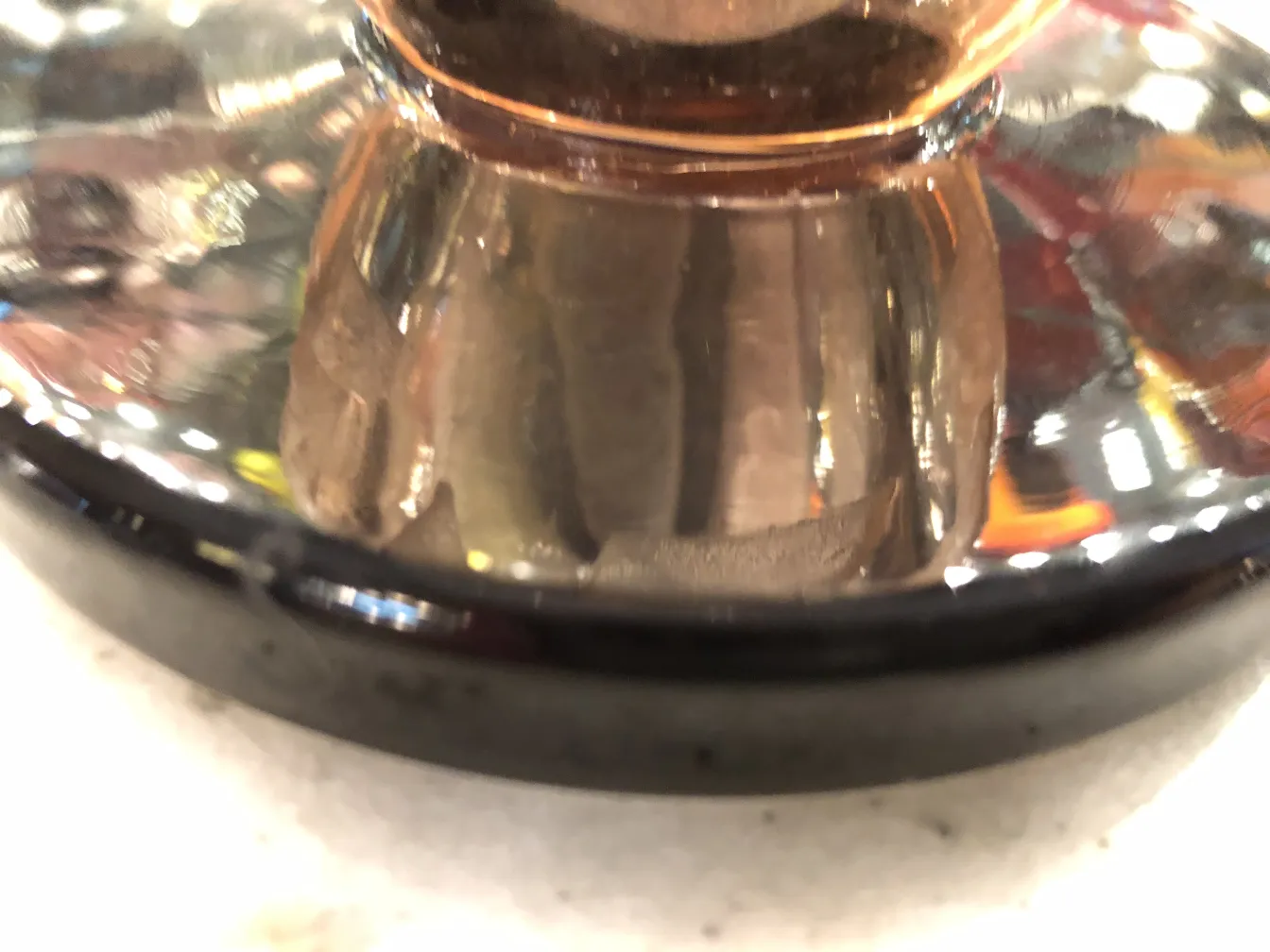 Antique signed glass by Schneider with a shiny reflection, vibrant backdrop.