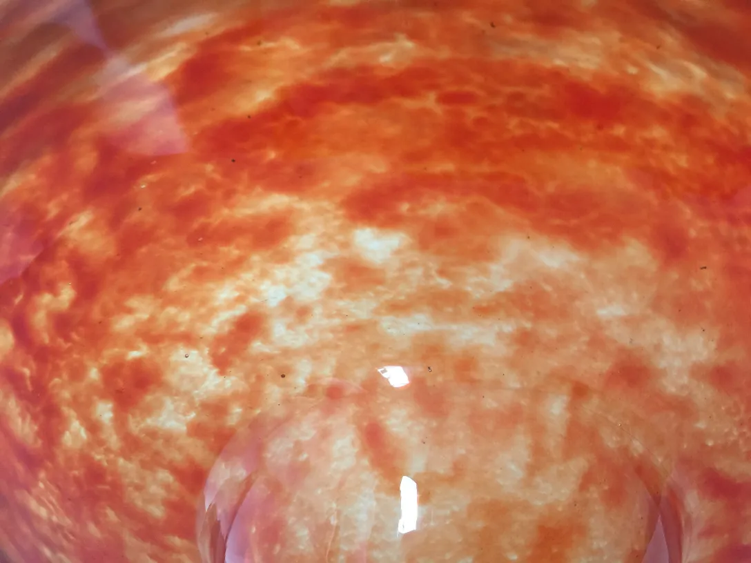 زجاج موقّع من قبل شنايدر يظهر تصميمًا زخرفيًا بألوان برتقالية وبيئته المحيطة.