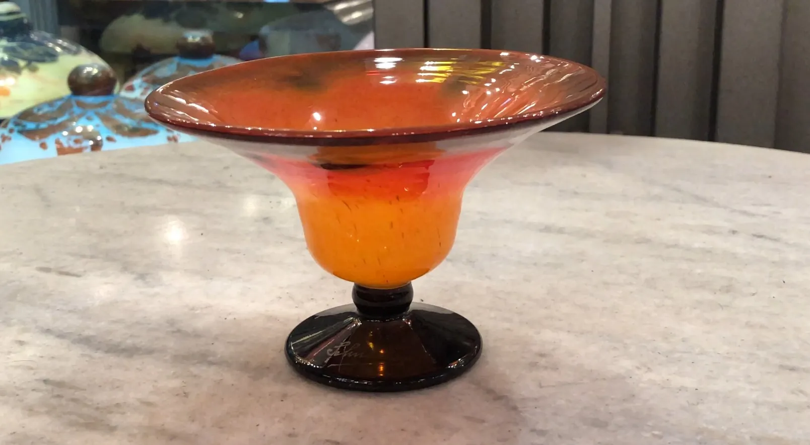 Verre signé ancien de Schneider avec un design coloré, posé sur une surface claire.