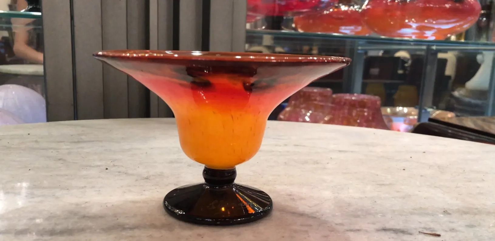 signiertes glas mit schwarzem sockel und warmen farben