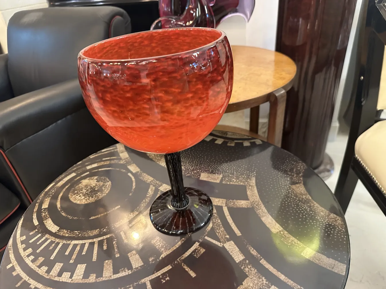 Rotes signiertes Glas auf schwarzem Sockel, stilvolles Ambiente.