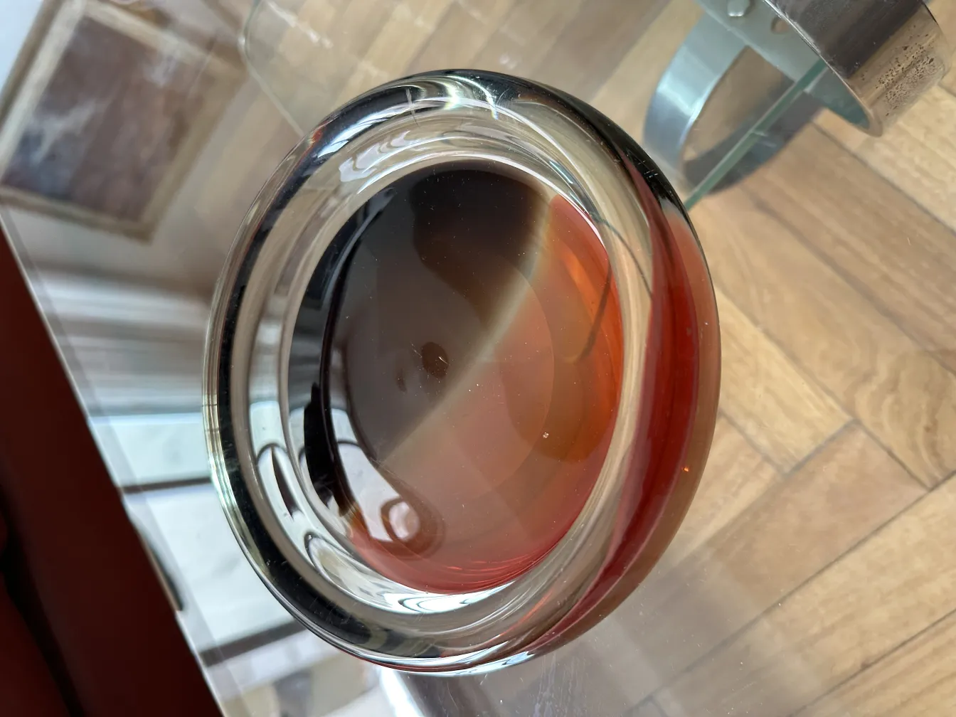 antikes murano-glas in runder form mit leuchtend roten farben auf einem hellen holztisch