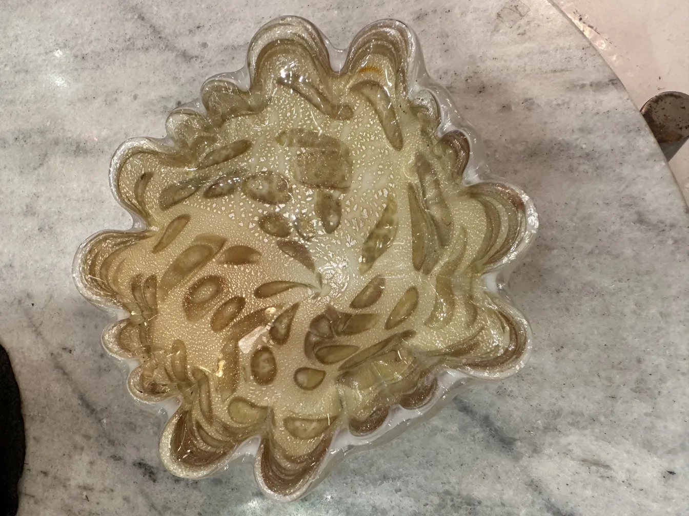 古董穆拉诺玻璃装饰品，具有波浪形、金色纹理细节，背景明亮。