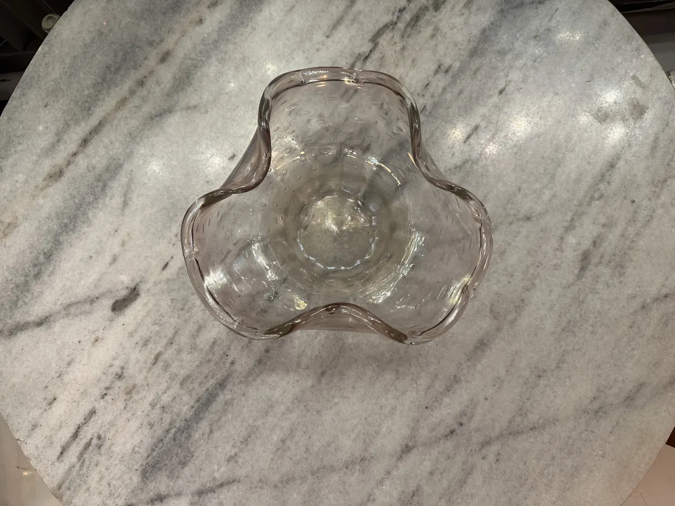 Peça antiga de cristal de murano com forma única e detalhes sutis em uma superfície branca.