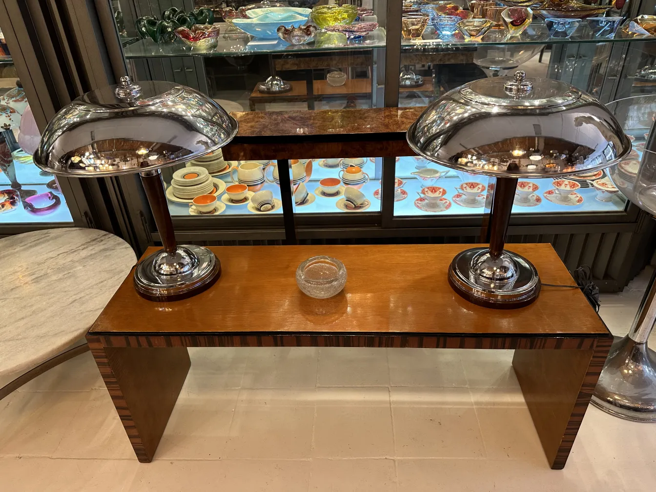 Dos lámparas antiguas con pantallas brillantes sobre una mesa de madera elegante, mostrando un ambiente elegante