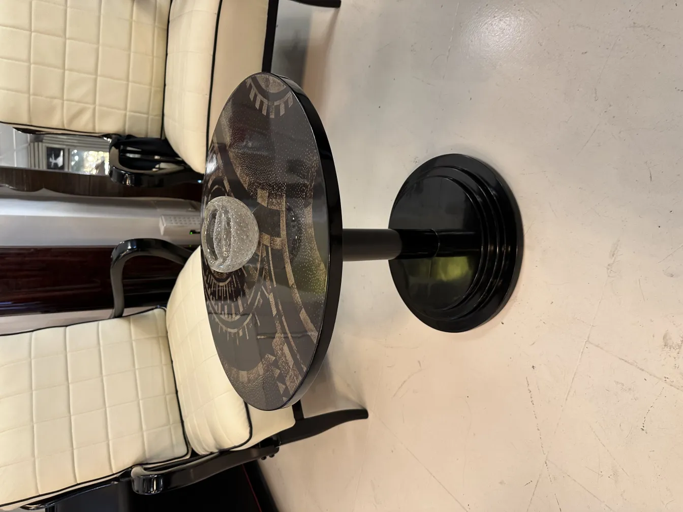 cristal de murano rond sur une table noire entourée de chaises claires