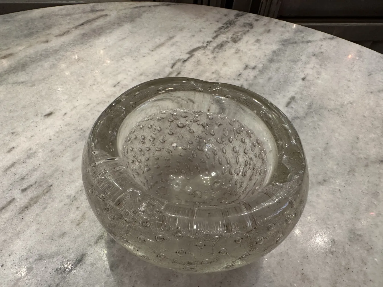 Cristal de Murano antiguo con burbujas, forma redonda y clara, sobre mesa de mármol