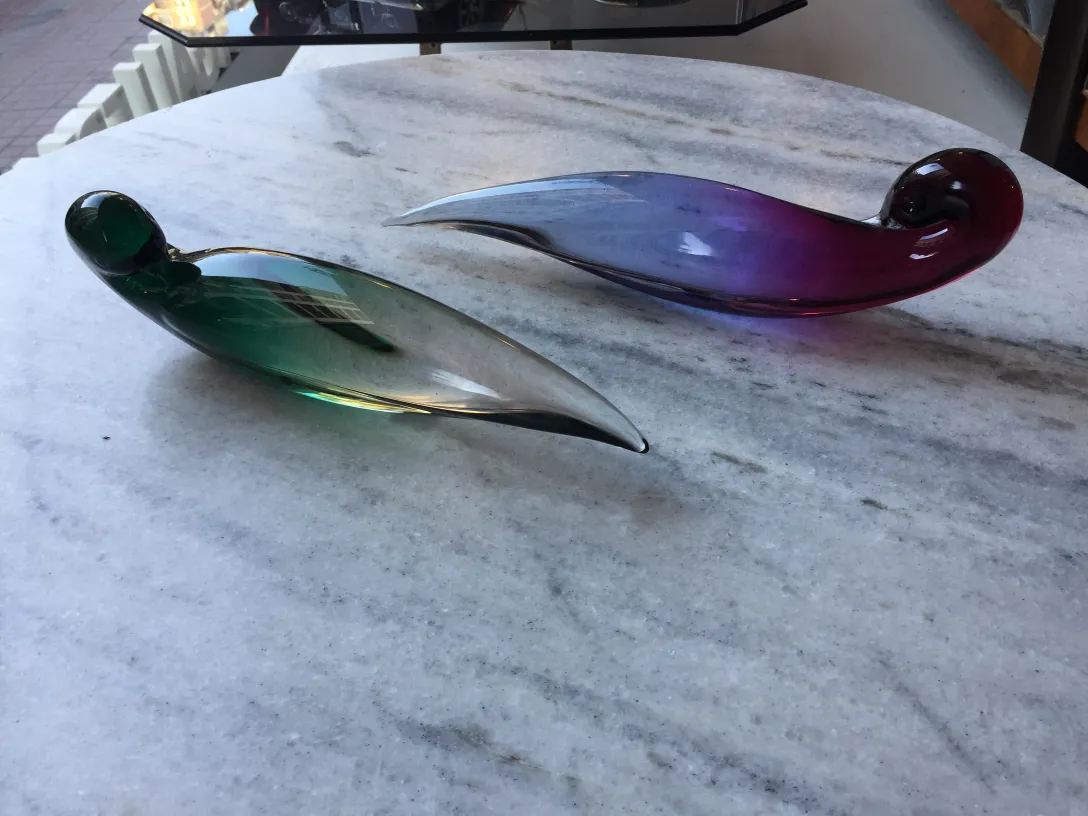 zwei antike murano-glas stücke in grün und lila auf einem marmor tisch