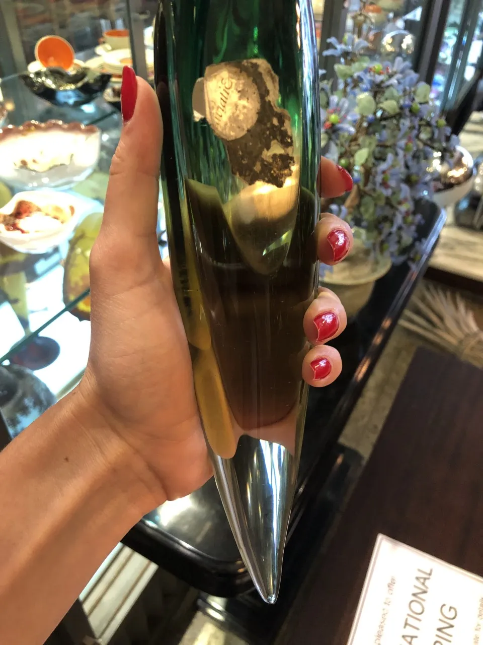 pieza de cristal de murano en forma cónica, verde y transparente, con un ambiente de antigüedades