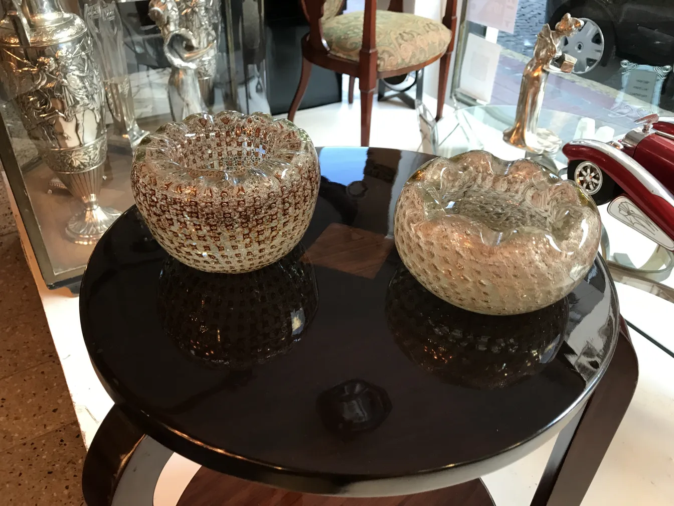 due antichi vetri di murano decorativi su un tavolo nero, con dettagli lucidi