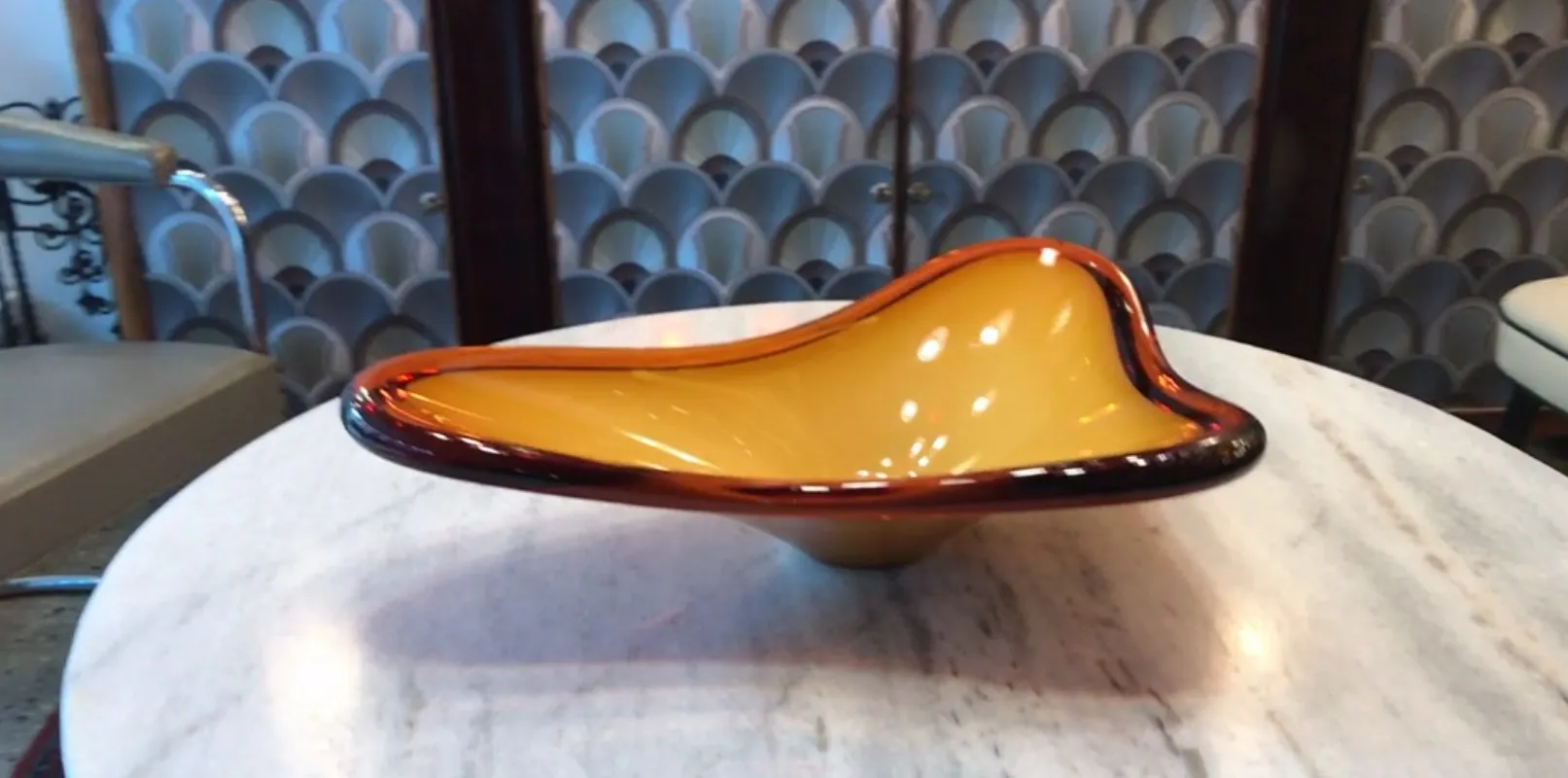 Beau cristal de Murano ancien en forme courbée, couleur ambre avec une finition brillante, présenté sur une table en marbre.