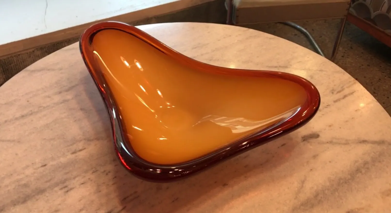 vaso de forma orgánica en tonos ámbar y rojo, sobre mesa