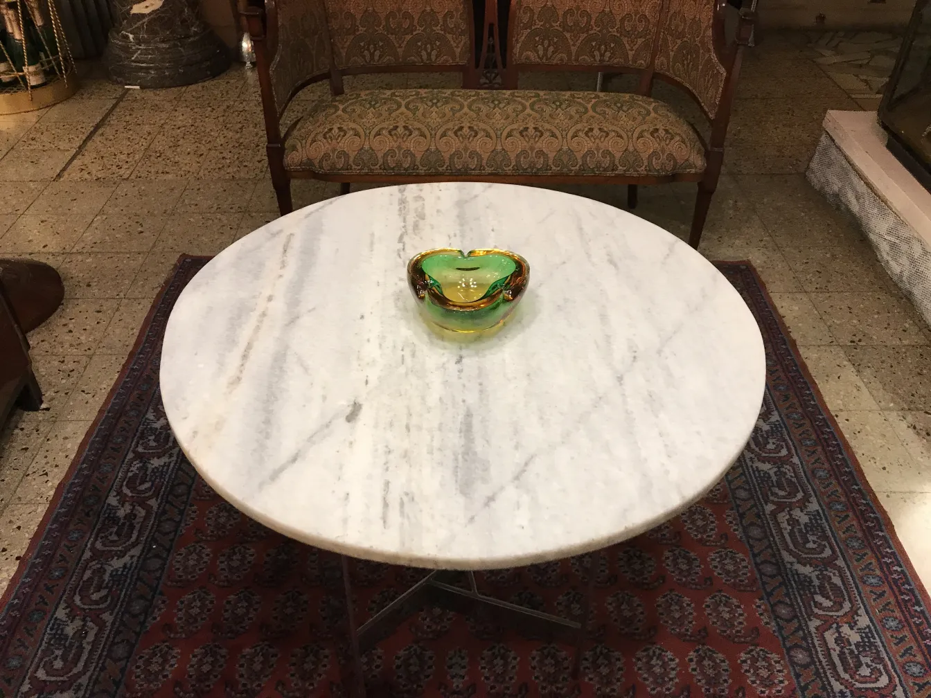 beautiful murano glass piece in green and yellow, elegantly shaped on a white marble table