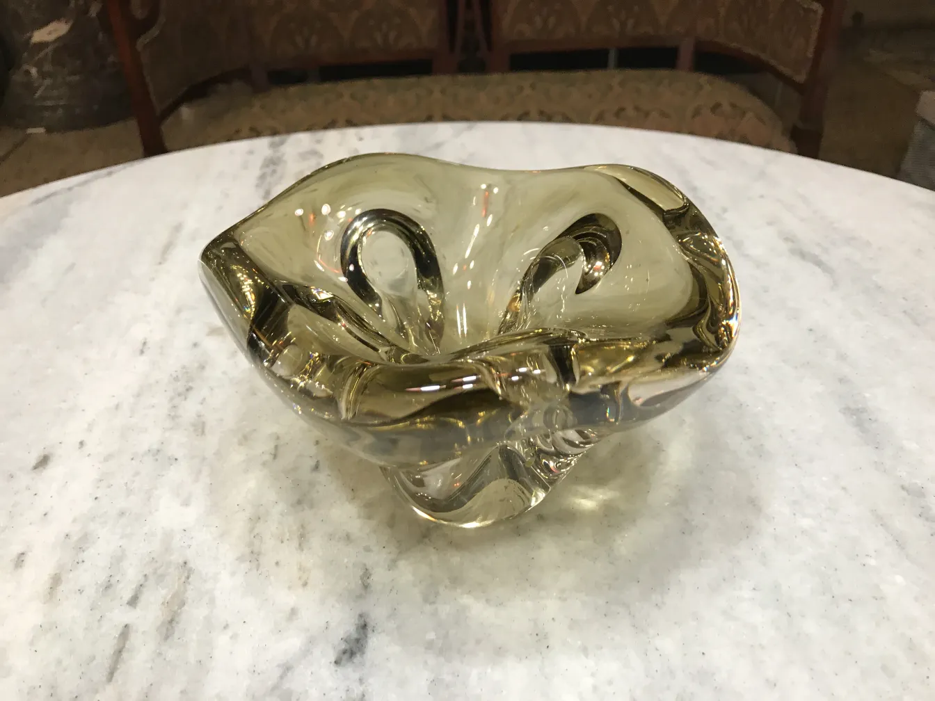 Antikes Murano-Glas mit sanften Kurven und warmem Gelbton, auf einem Marmortisch.