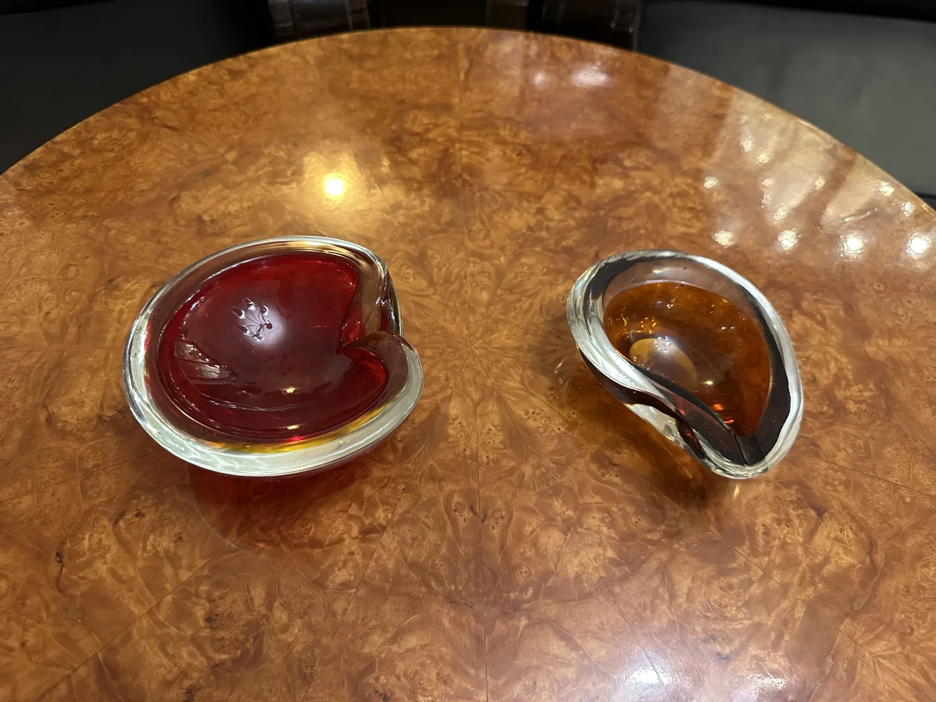 两个古老的穆拉诺玻璃，一个红色，一个琥珀色，放在木桌上