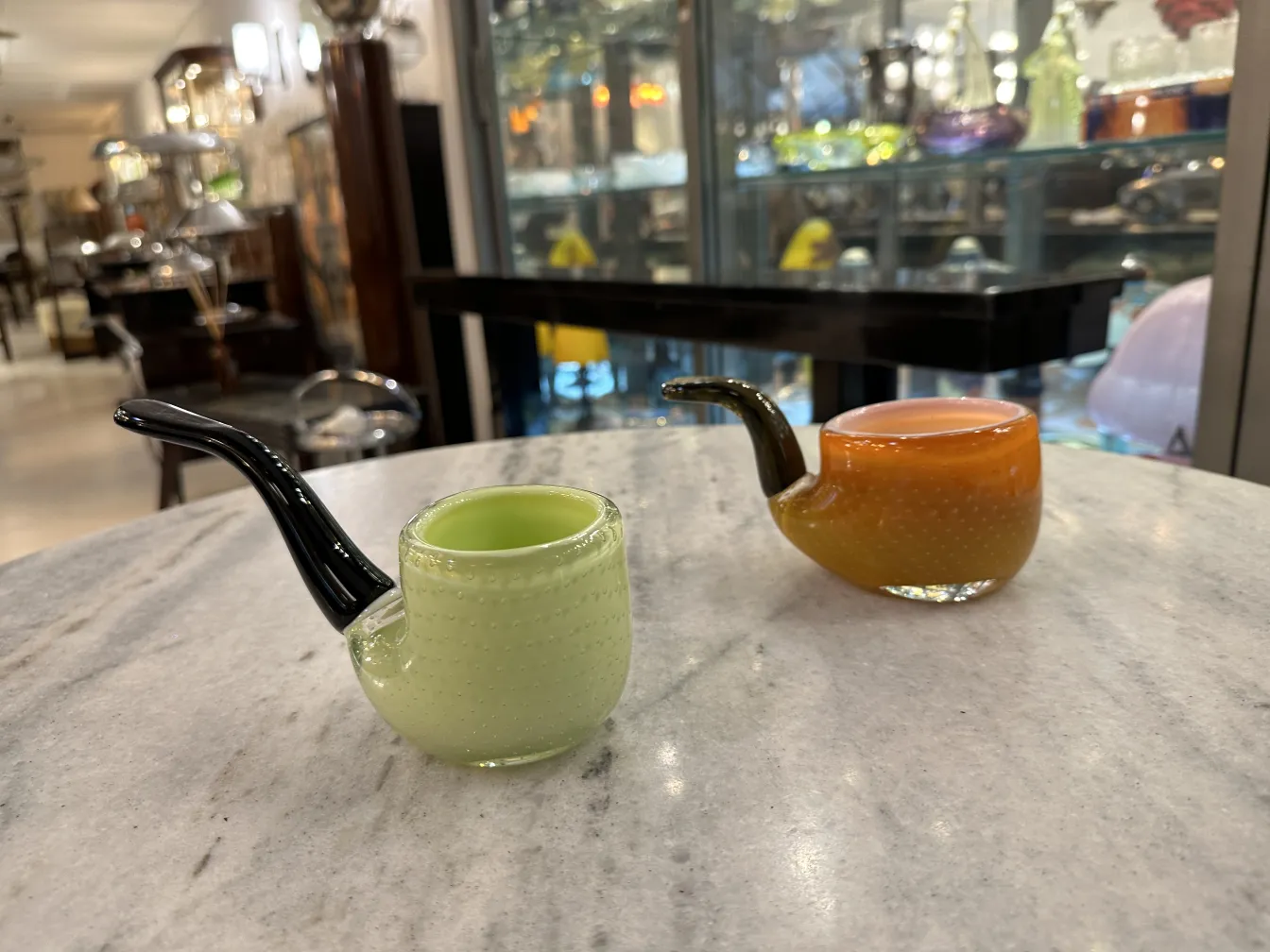 deux anciennes pipes en cristal de murano de couleurs douces sur une table