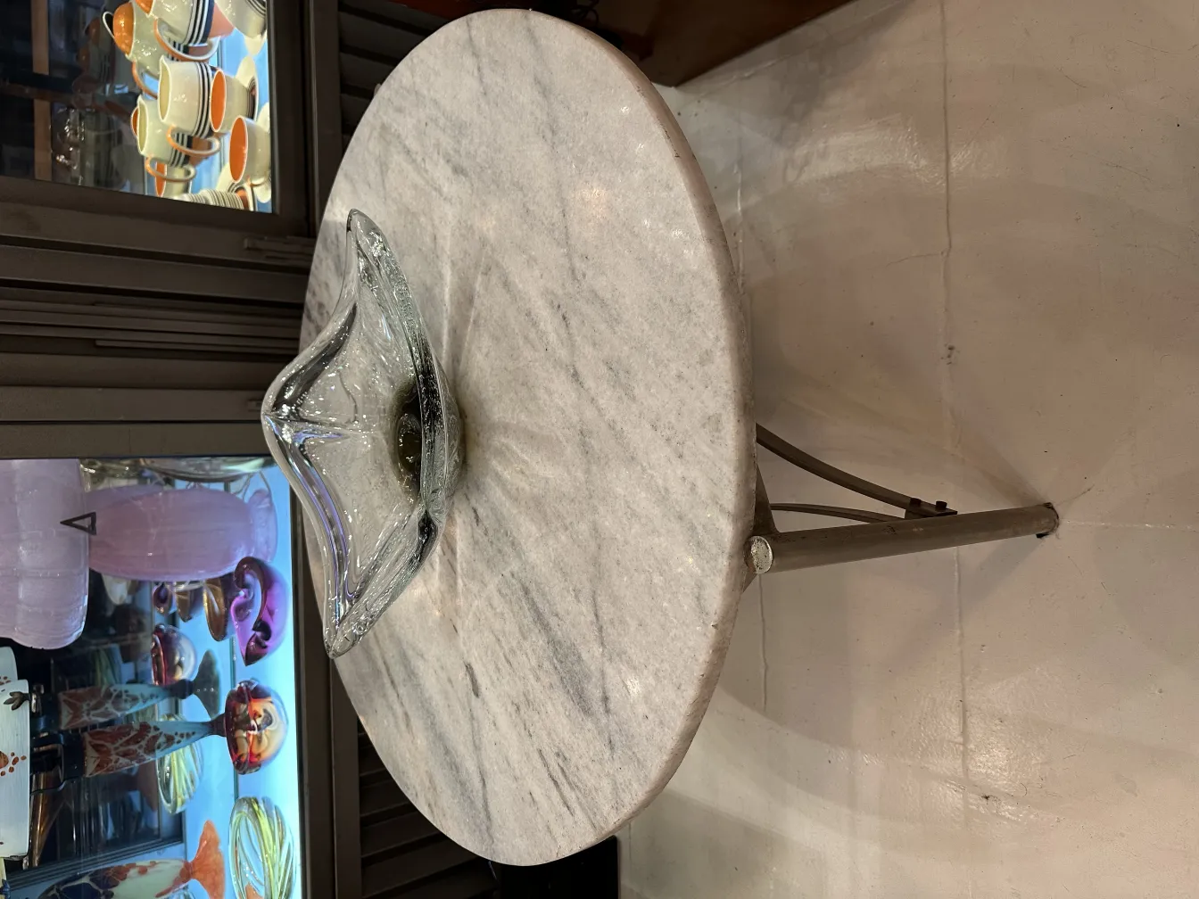 Bowl de cristal de murano em forma ondulada sobre mesa de mármore, fundo com antiguidades