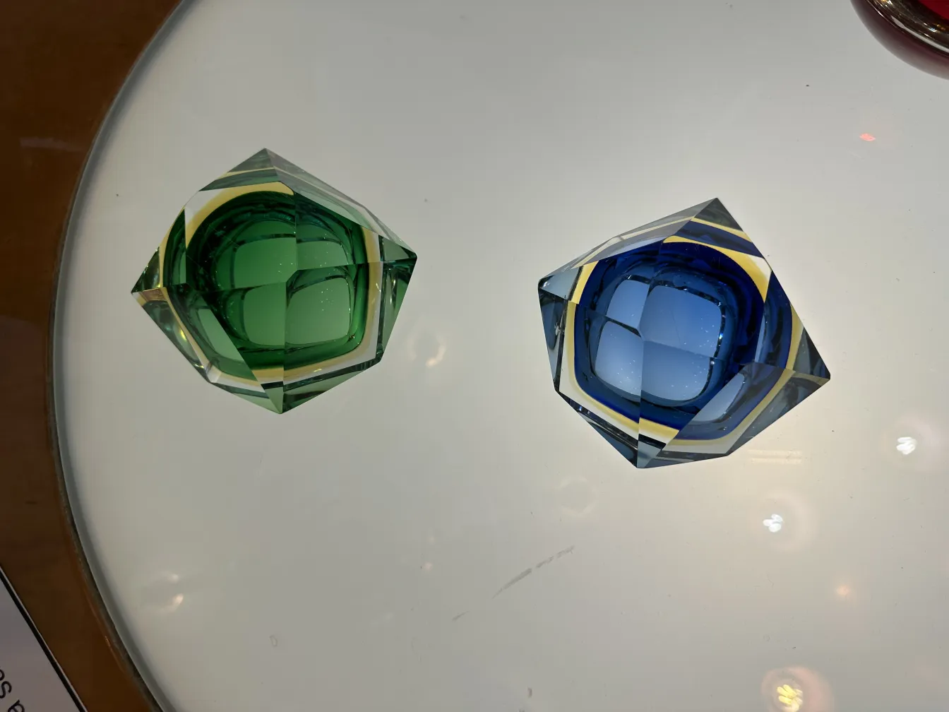 Two pieces of antique Murano glass, one green and one blue, with geometric shapes.