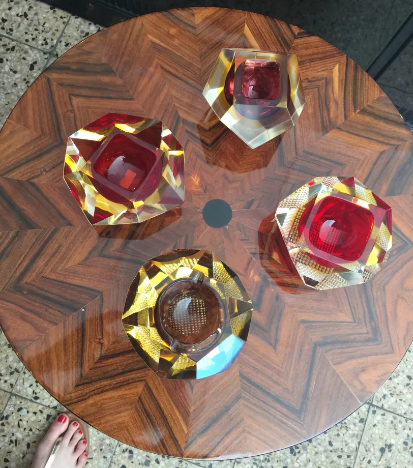 quatro peças de cristal de Murano em várias formas em uma mesa de madeira