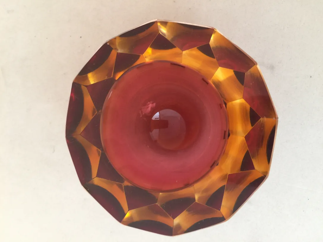 vue de dessus d'un ancien cristal de Murano avec des couleurs rouges et ambrées, en forme octogonale.