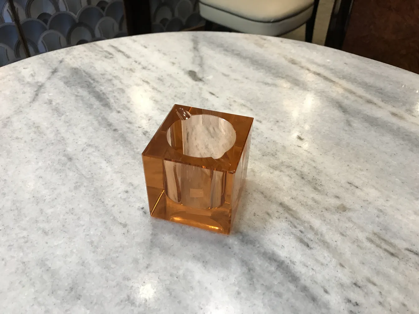 Cristal de Murano antiguo con forma cuadrada y color naranja, sobre una mesa de mármol.