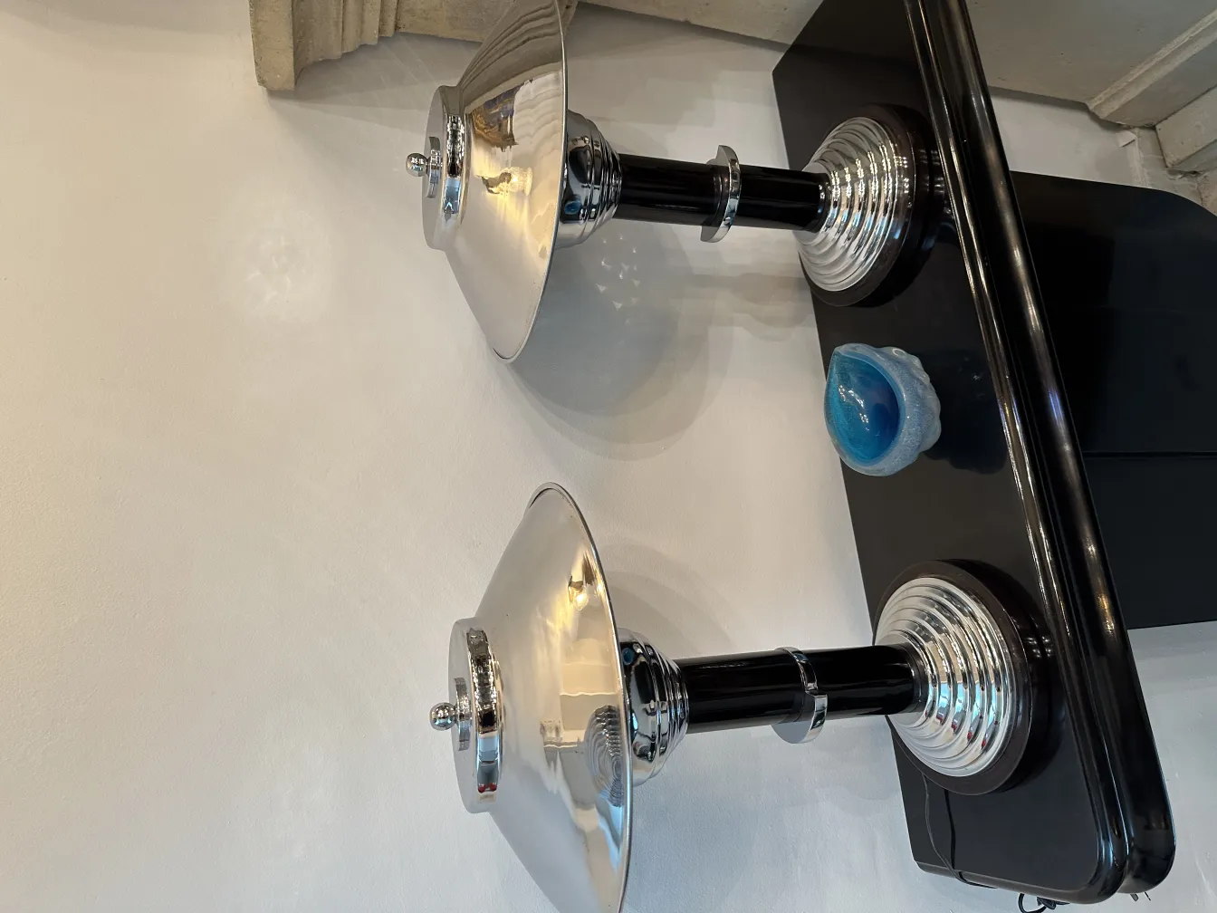 duas lâmpadas brilhantes em uma superfície preta com um objeto decorativo azul ao lado