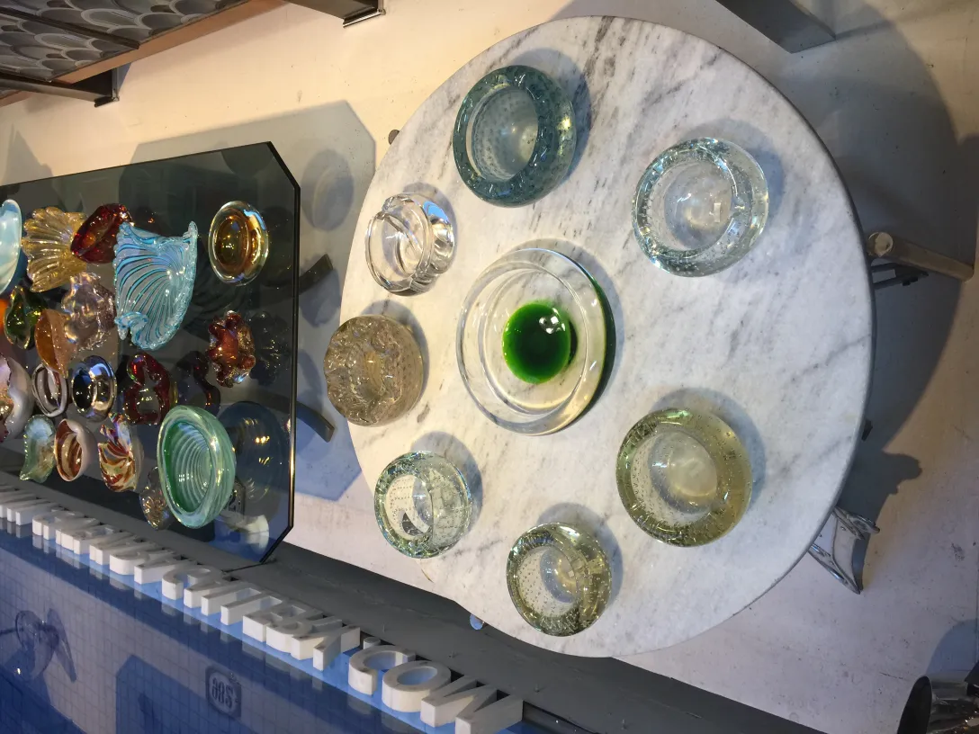 Various shapes and colors of antique Murano glass on a table.