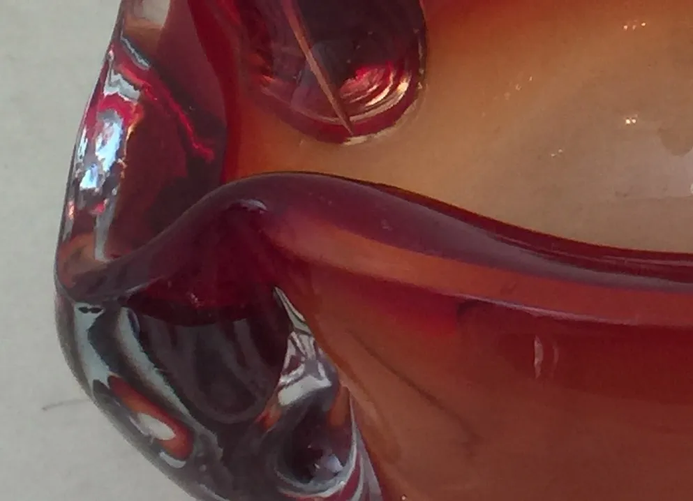 Cristal de Murano antiguo con tonos rojos, forma curvilínea y detalles brillantes