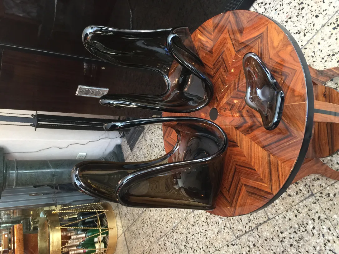 Vetro di Murano antico con forme fluide e brillanti, esposto su un tavolo elegante.