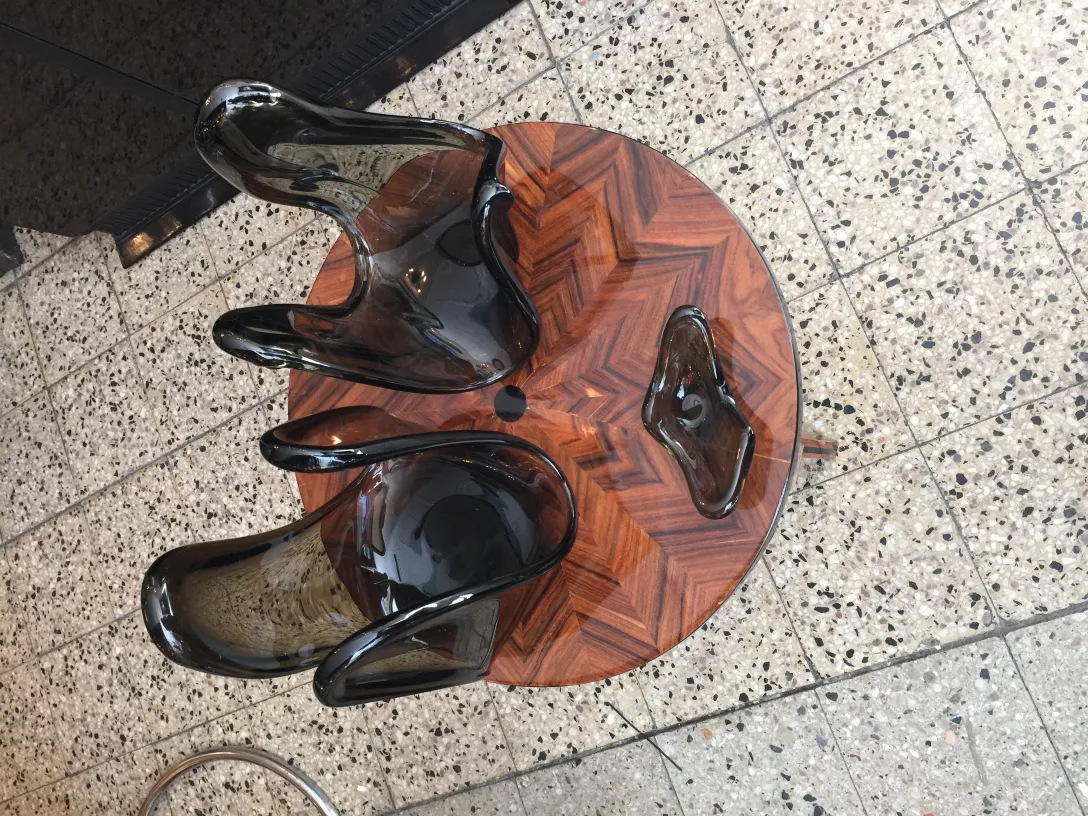 антикварная скульптура из муранского стекла, темные цвета и плавные формы, элегантный стиль на деревянном столе