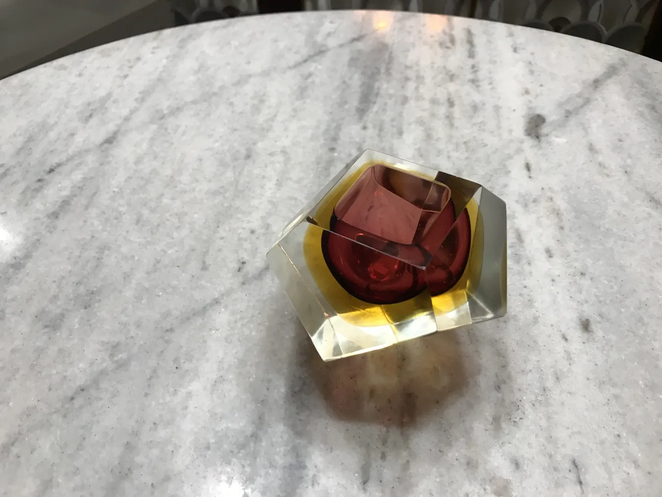 Cristal de Murano ancien avec des tons chauds et une forme angulaire sur une table en marbre.