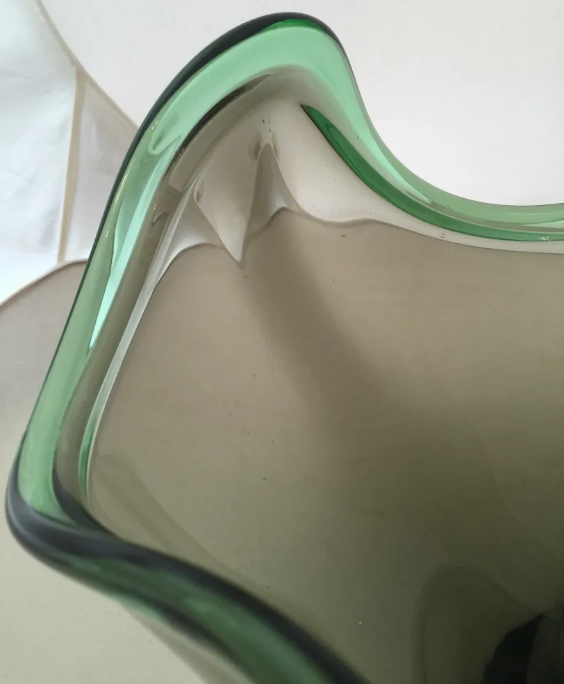 detalhe de uma antiga peça decorativa de cristal de murano com bordas verdes e forma ondulada