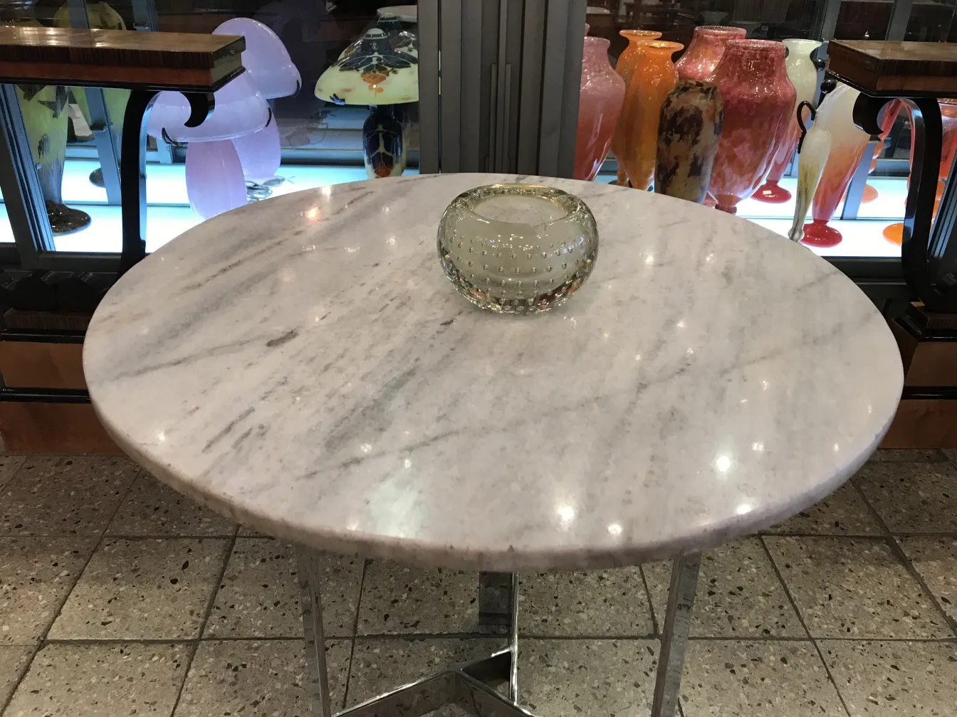 穆拉诺玻璃碗放在大理石桌子上，背景是花瓶