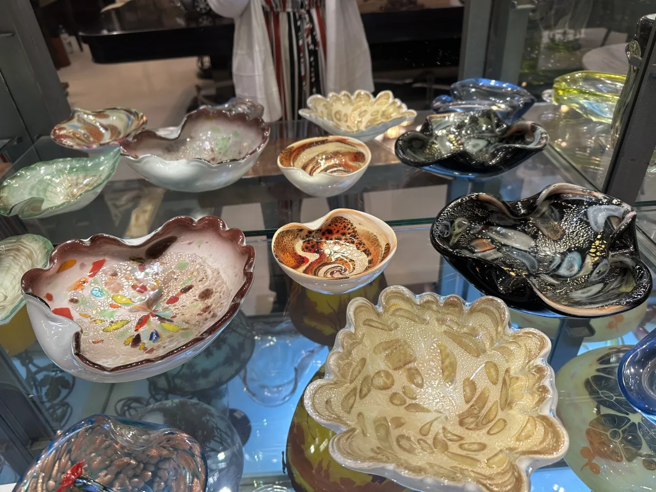 Display of colorful antique Murano glass pieces with elegant shapes and decorative patterns.