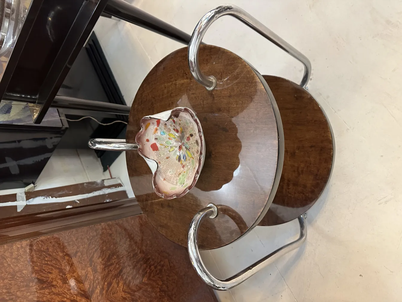 Antigo cristal de Murano com cores vibrantes em forma de flor sobre mesa de madeira.