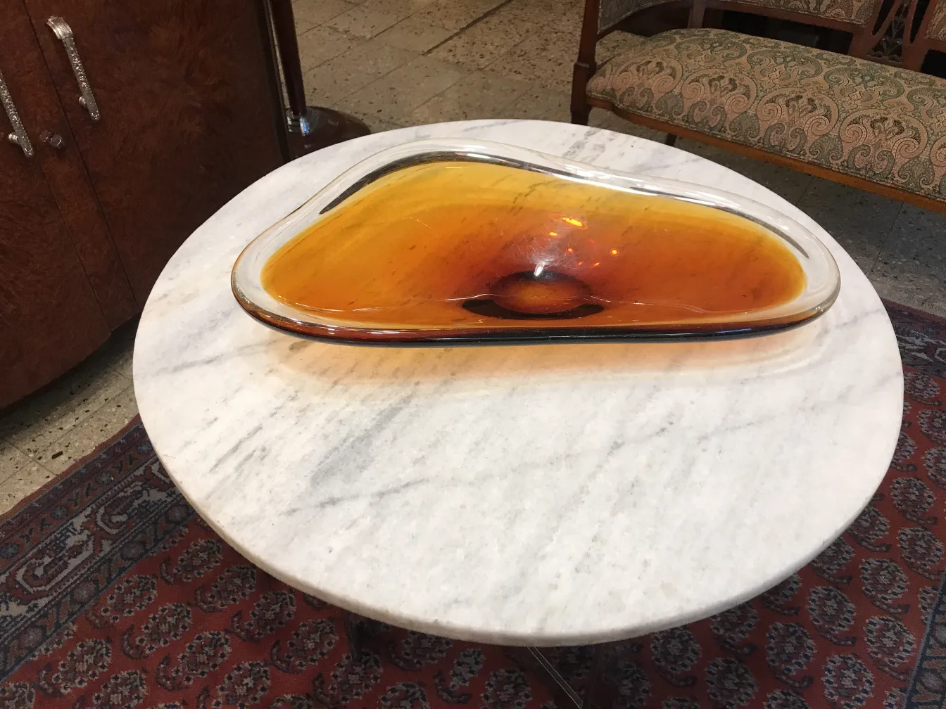 Plat en cristal de Murano aux tons ambrés sur une table en marbre.