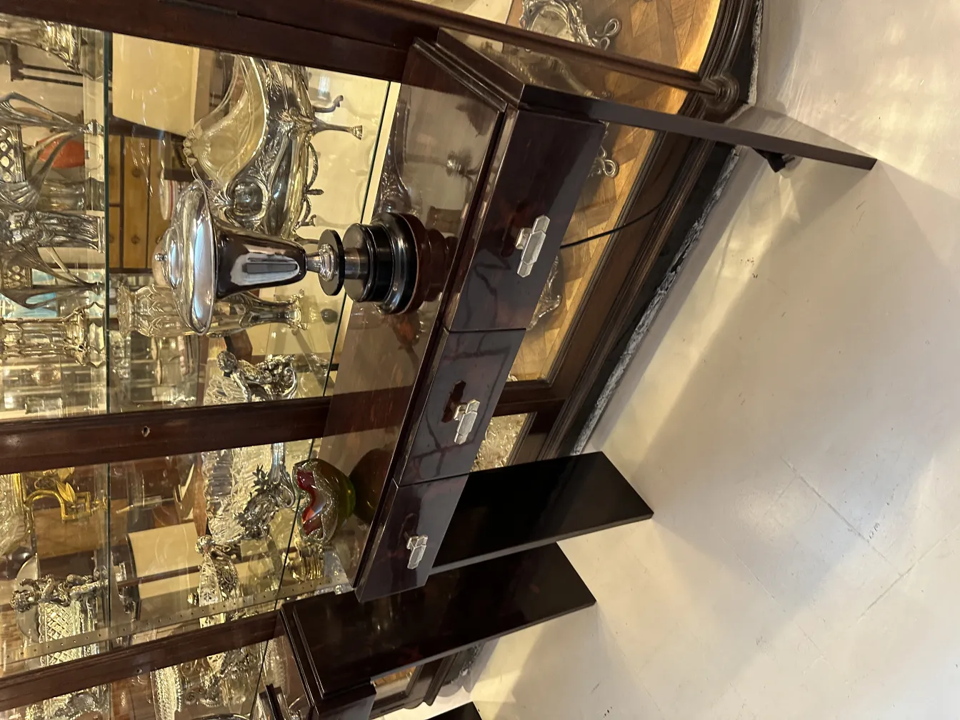 Antiguo cristal de Murano con forma redondeada, detalles plateados y fondo elegante con otras antigüedades.