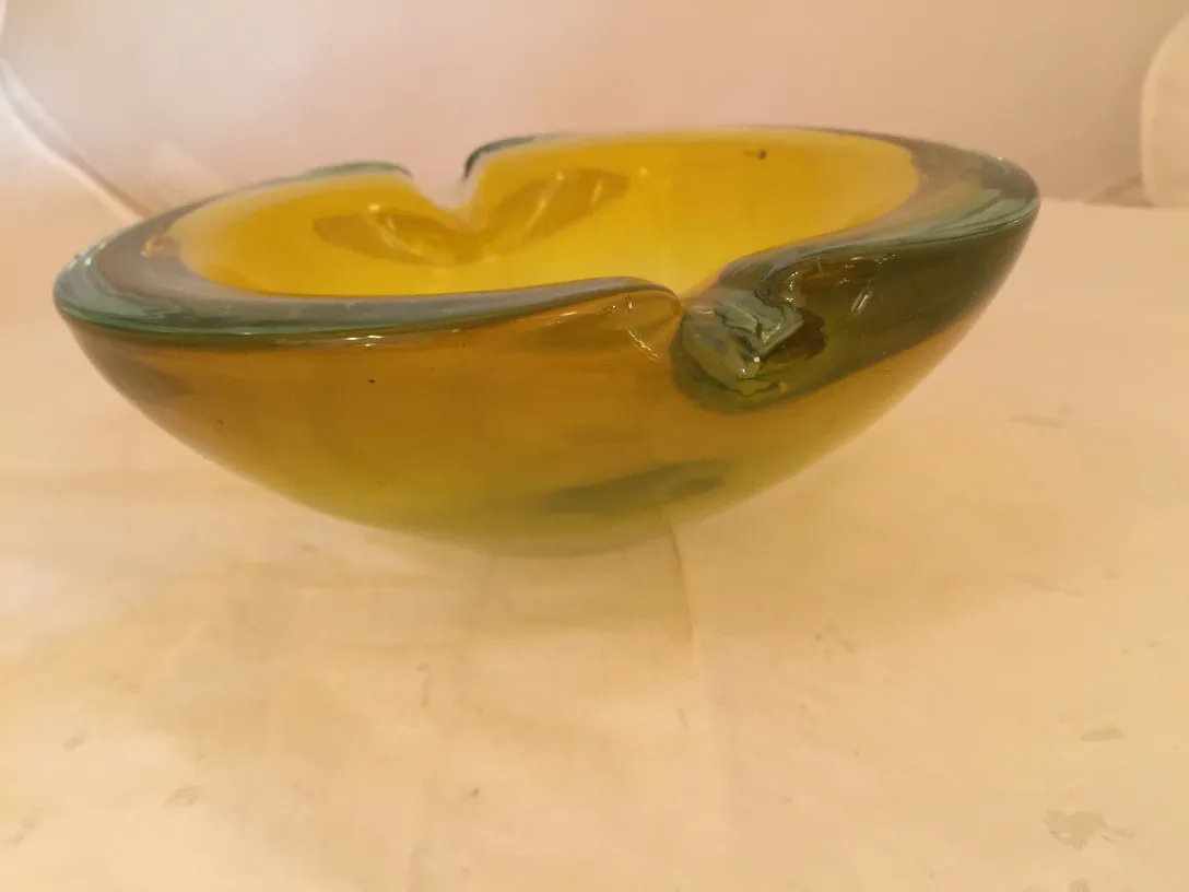 Cristal de Murano decorativo em tom amarelo com detalhes verdes em um ambiente neutro