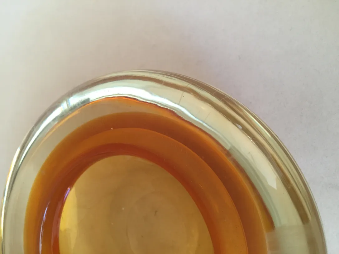 Top view of an antique Murano glass in amber tones, with smooth edges and a warm ambiance.