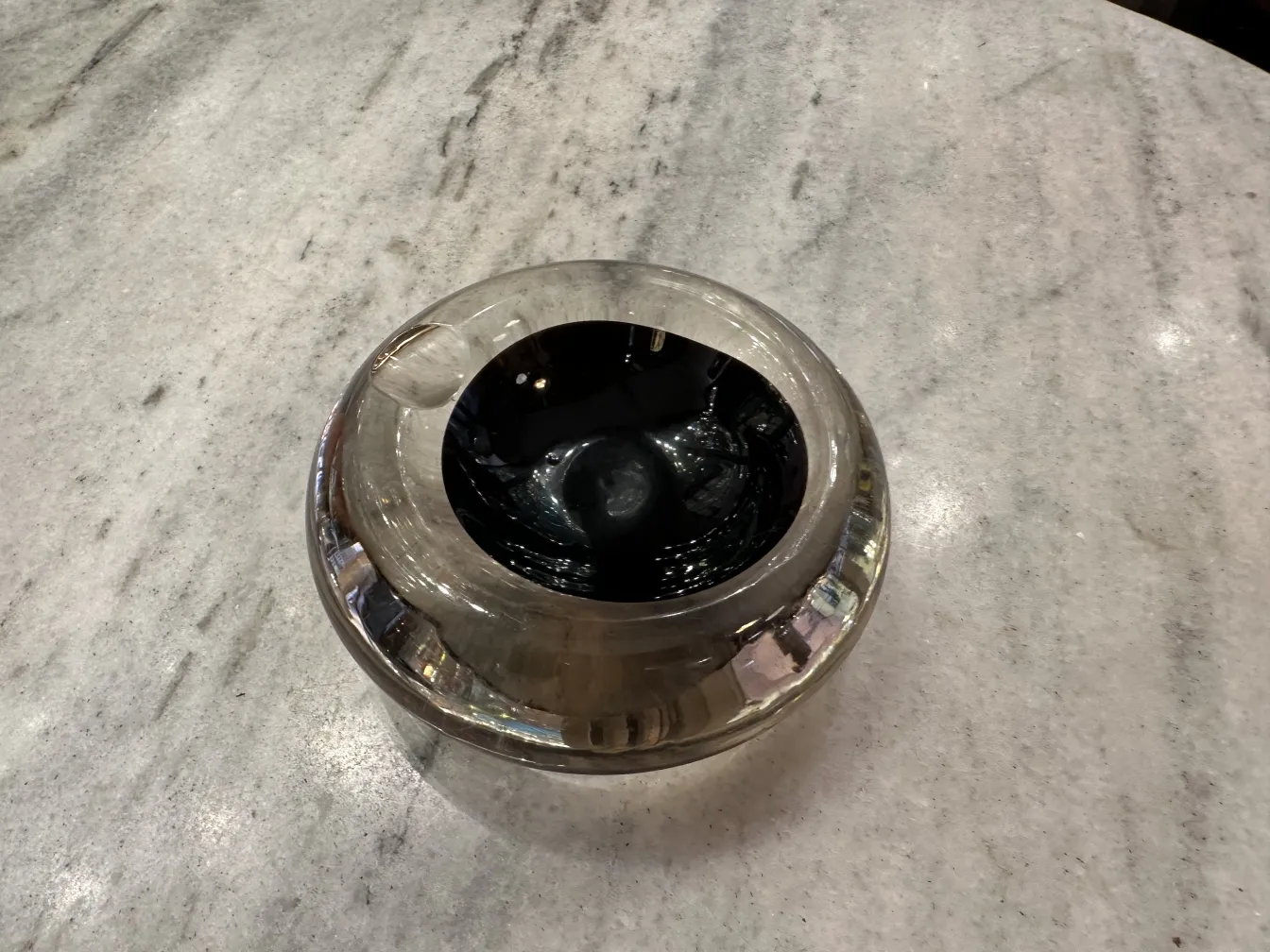 黒いデザインの古いムラーノガラスが明るい表面に置かれています。