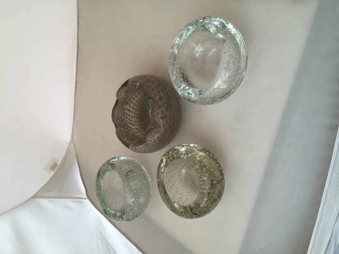 Ensemble de quatre pièces en cristal de Murano dans différentes nuances, montrant des détails fins et des designs intéressants dans un cadre ancien.