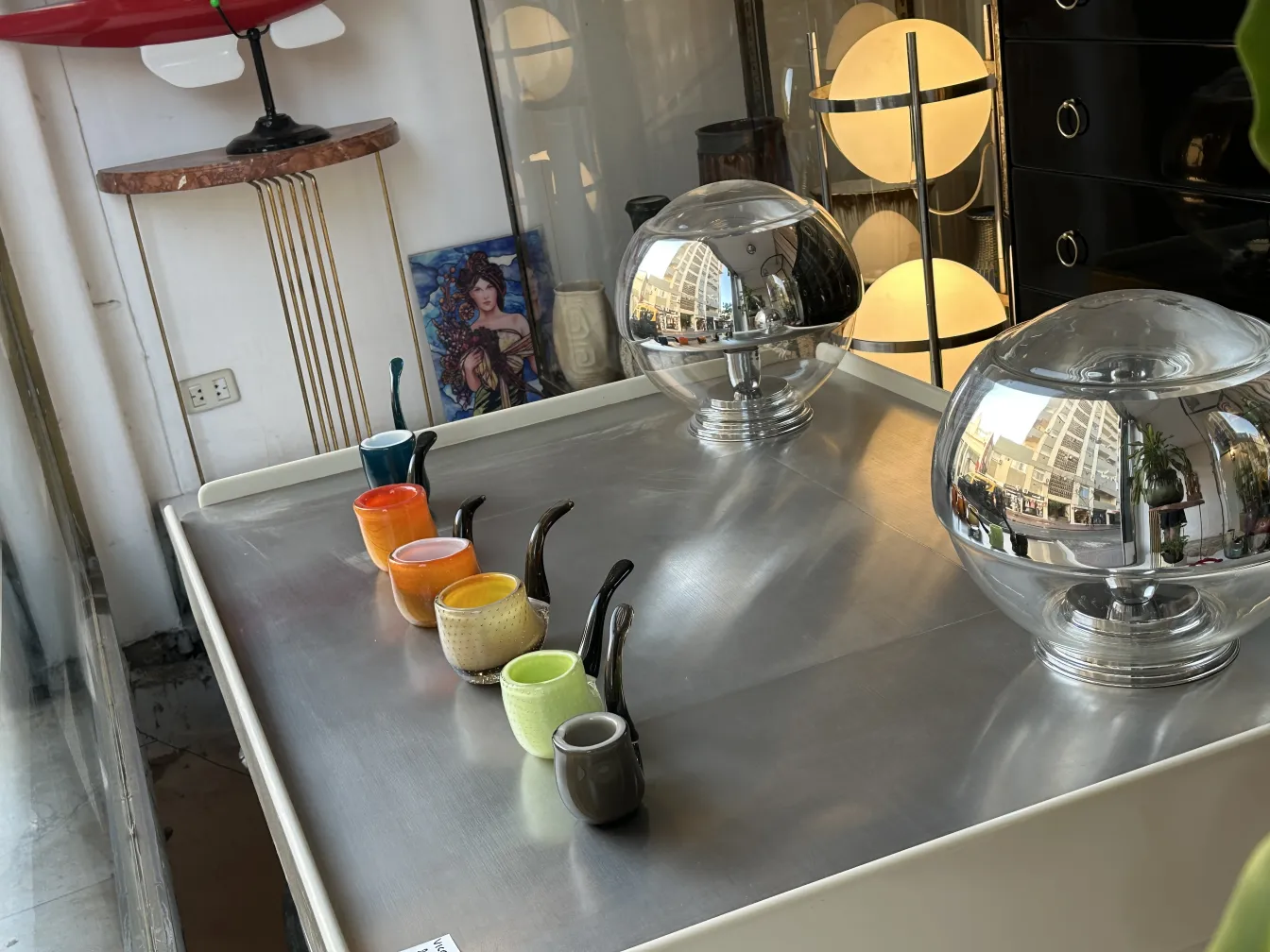 Vários vasos antigos de cristal de Murano em cores vibrantes sobre uma mesa de metal