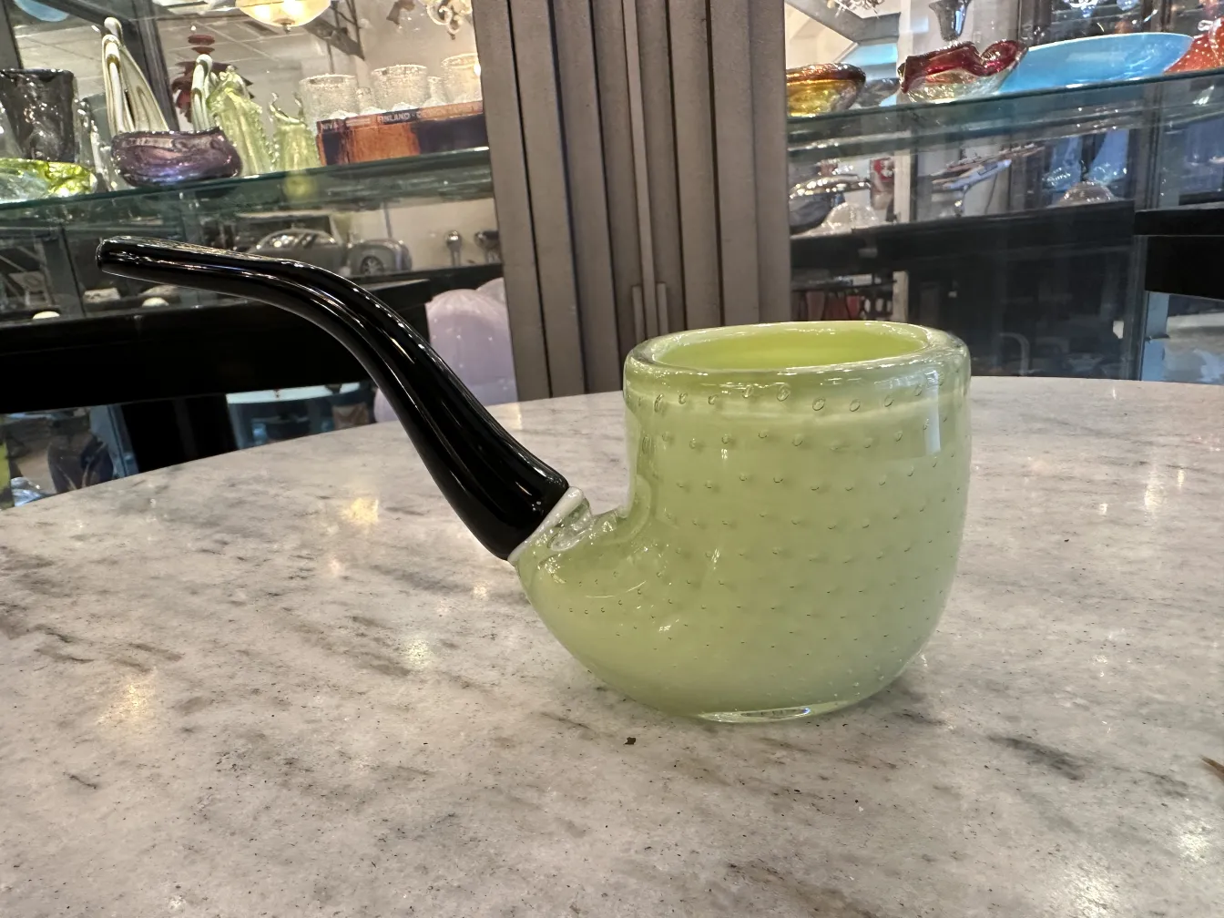 Ancien cristal de Murano en forme de pipe, vert clair avec des détails noirs, sur une table en marbre