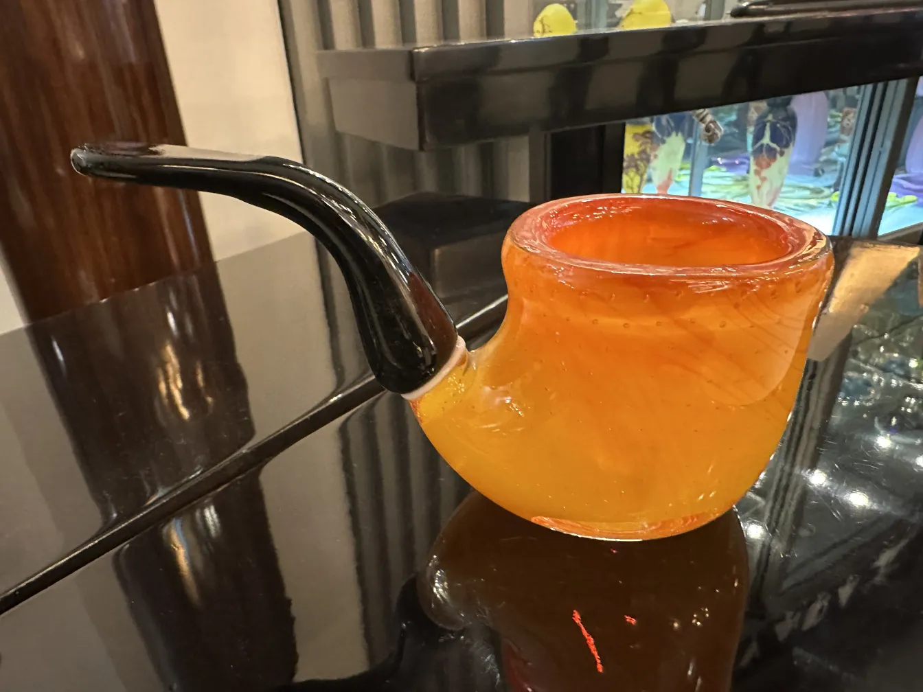 antique murano glass piece in orange and black, pipe shape, on shiny surface