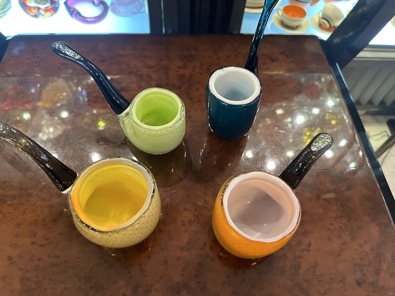 Quatro xícaras de cristal de Murano antigas em várias cores, com detalhes decorativos.