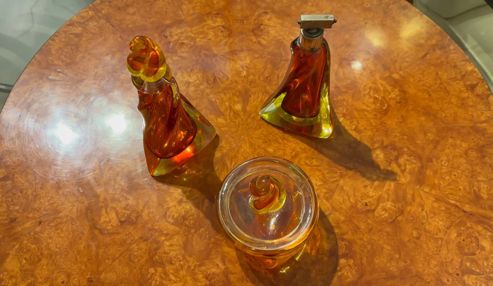três antigos cristais de murano decorativos em tons quentes sobre uma mesa