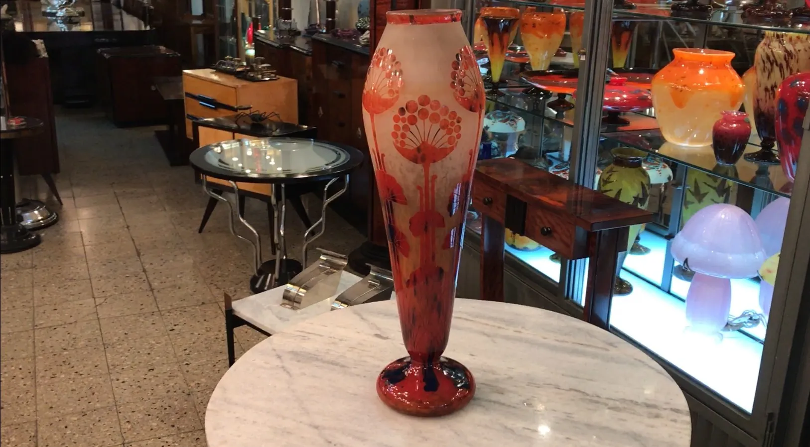 Jarrón de vidrio firmado con motivos florales en un entorno antiguo.