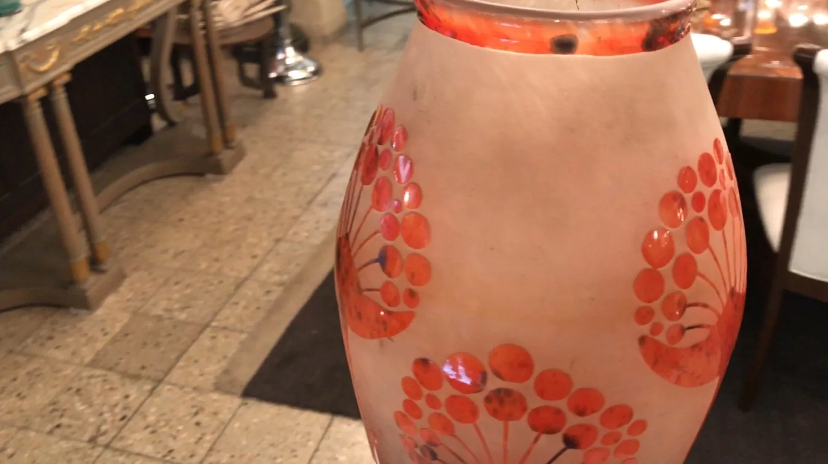 Antiguo vidrio firmado con decoraciones en tonos rojos, ambiente clásico.