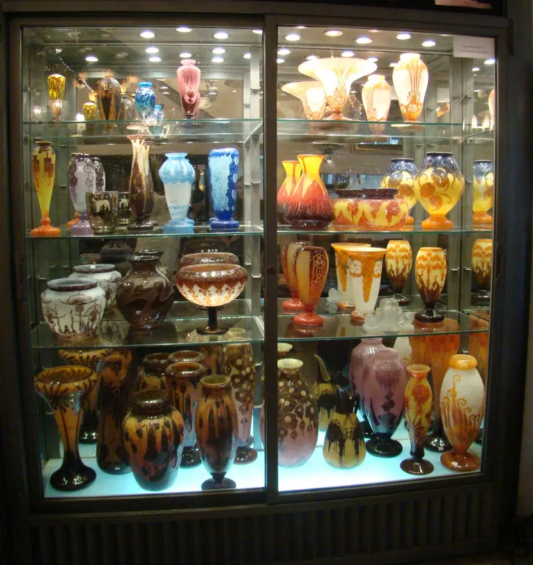 Vitrine mit Antiquitäten, verschiedene farbige Glasgegenstände.