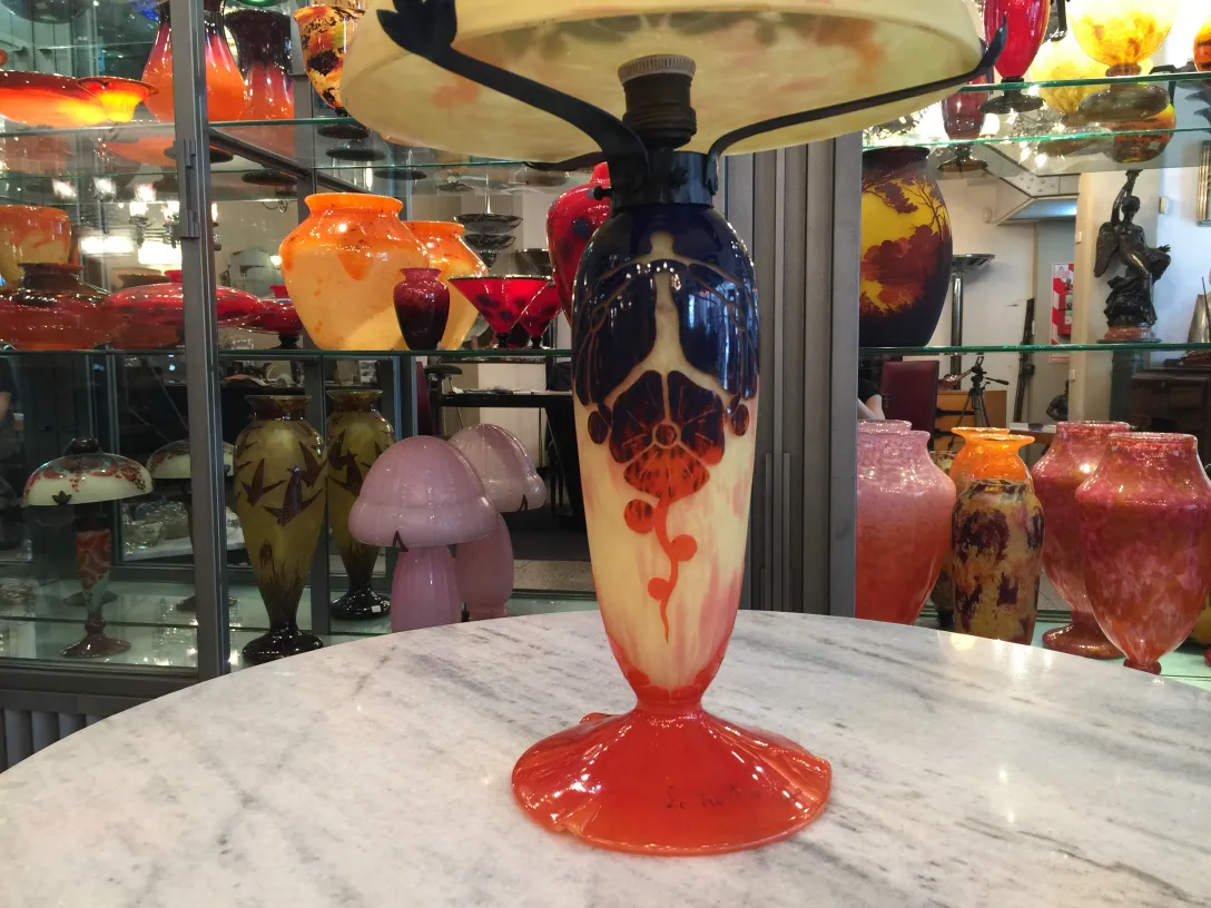 Lâmpada vintage com base de vidro assinado Le Verre, fundo com mais itens de vidro.